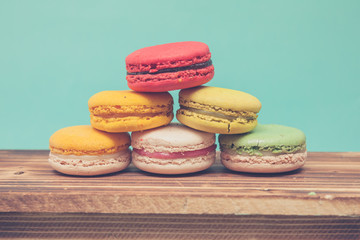 Pile of colorful macarons stacked up like a tower in blue turquoise pastel isolated background on wood table