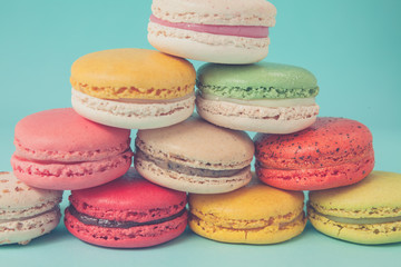 Pile of colorful macaroons stacked up like a tower in blue turquoise pastel isolated background