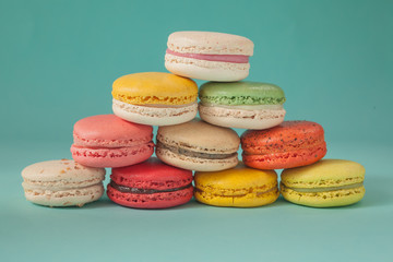 Pile of colorful macaroons stacked up like a tower in turquoise pastel isolated background (Selective focus) - Closeup for detail