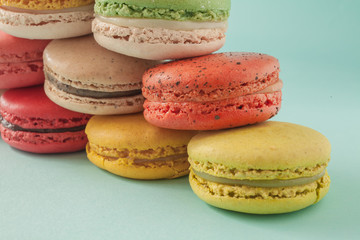 Pile of colorful macaroons stacked up like a tower in turquoise pastel isolated background (Selective focus) - Closeup for detail