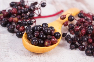 Heap of elderberry with wooden spoon on old wooden background, healthy food