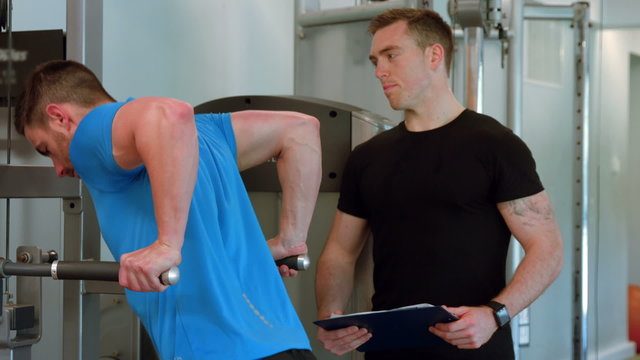 Fit man doing pull ups with trainer