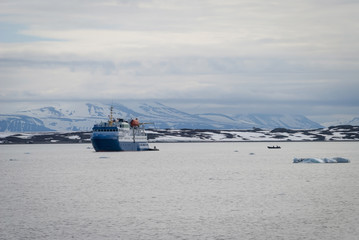 Ship sailing between icebergs in the arctic sea in Svalbard
