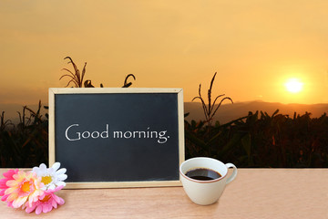blackboard and coffee on meadow in sunrise background