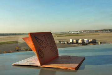 An opened foreign passport with the view of an airport