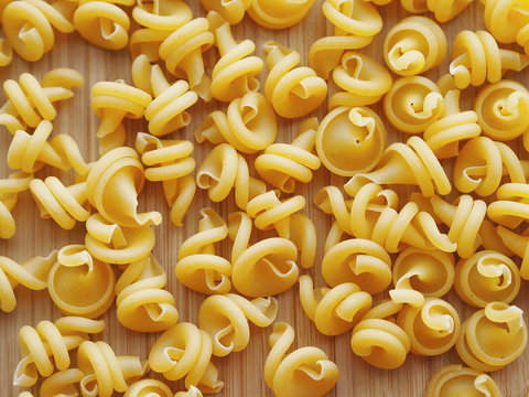 Funghetto pasta type ("mushroom-style") on a wooden background.