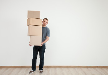 Smiling young man carrying many cardboard boxes