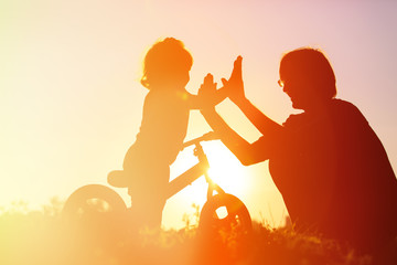 Fototapeta premium father and daughter having fun riding bike at sunset