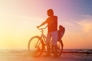 Fototapeta na wymiar Silhouette of father and baby biking at sunset