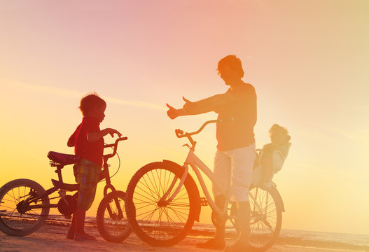 father with two kids on bikes at sunset
