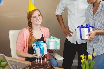 Portrait of happy businesswoman receiving birthday gifts 