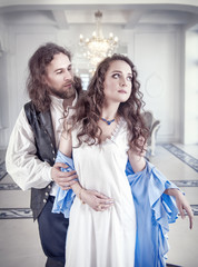 Fototapeta premium Handsome man in medieval costume undress beautiful woman