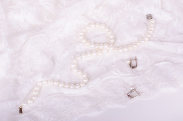 Pearl necklace and earrings on white lace cloth 