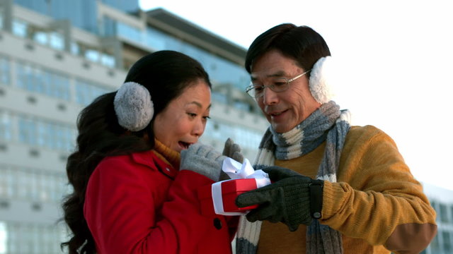 Couple in warm clothing holding gift 
