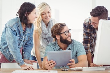 Happy business people using digital tablet at computer desk 