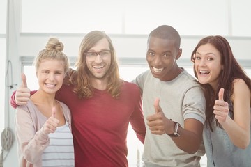 Portrait of smiling business team with thumbs up and arms around