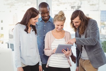 Happy woman holding digital tablet and discussing with coworkers