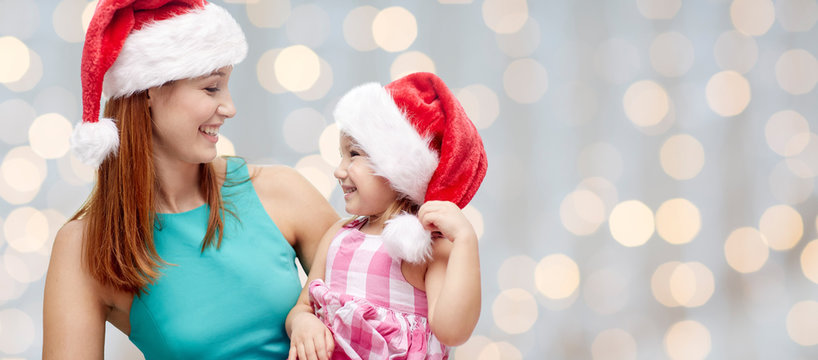 happy mother and little girl in santa hats - Powered by Adobe