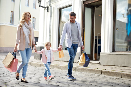 Happy Family With Child And Shopping Bags In City