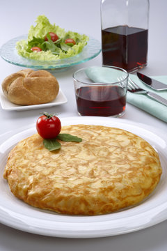 Potato omelette, bread, glass of wine and salad.