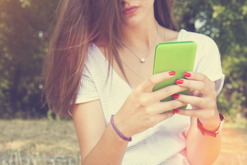 Young woman using cellphone outdoors.