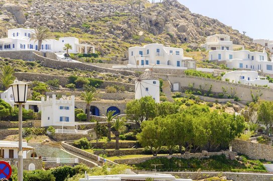 Ornos, Mykonos, Greece. The cube whitewashed traditional houses and windmill in Ornos, Mykonos, Greece. Very typical greek island architecture on a rocky hill.