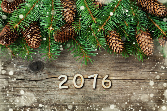 Christmas decoration of fir tree and conifer cone on textured wood background, magic snow effect and wooden numbers of New year, top view