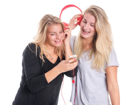 Zwei blonde Mädchen hören zusammen Musik über einen Kopfhörer