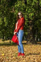 Young woman in fashion red jacket and red bag walking in autumn