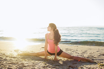 young caucasian female doing exercises on the seaside during the