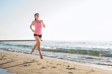 Fototapeta na wymiar Running woman. Female runner jogging during the sunrise on beach