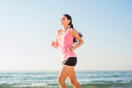 Running woman. Female runner jogging during the sunrise on beach