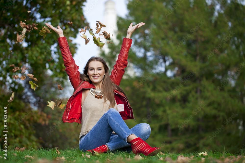 Wall mural hppy beautiful woman in red leather jacket and blue jeans sittin