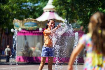 Two sisters playing with fountain splash