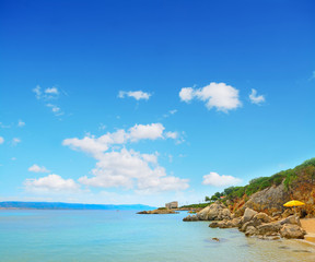 Naklejka premium yellow umbrella by the shore in Alghero