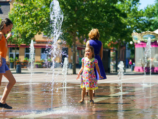 Two sisters playing with fountain splash