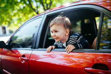 Baby boy in the car looking throw window.