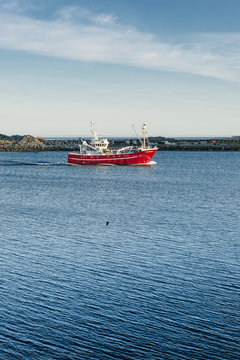 Red fishing cutter on blue water - Lofoten Island.