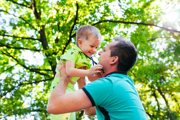 Cheerful father having fun with his little son in the park.