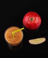 apple smoothie in glass and apples on black acrylic sheet