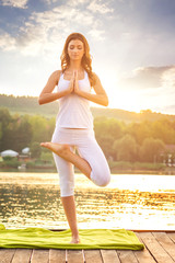 Woman doing yoga on the lake - beautiful lights