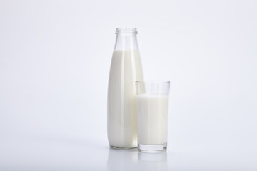 Open bottle and glass of milk on white background.