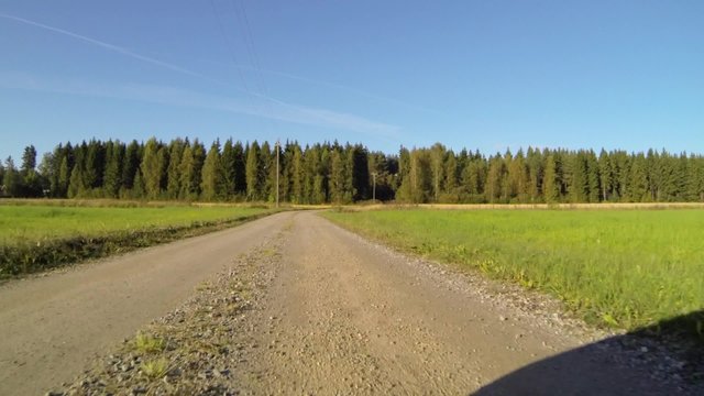Bumper camera view of car driving on countryside gravel road