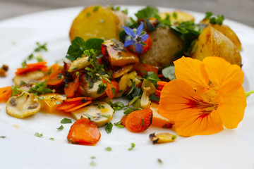 Veganes Mittagessen, Gemüse, Möhren, Paprika und Pilze und frische Kräuter mit Kartoffeln - Borretsch, Kapuzinerkresse (Tropaeolum), Essbare Blüten