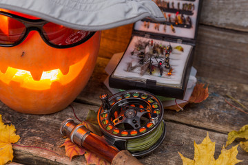 halloween pumpkin in hat with fly-fishing tackles