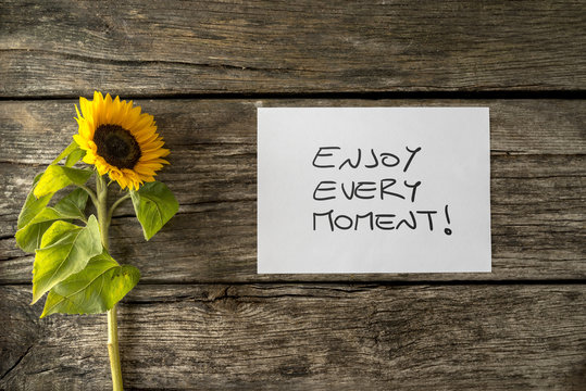 White card with an Enjoy every moment message lying next to a be