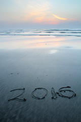 Sandy beach with 2016 written on sand during dawn hours 