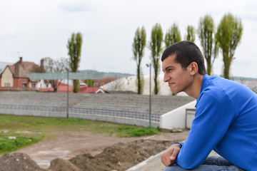 Fototapeta premium Unhappy teenage student sitting outside on stadium steps