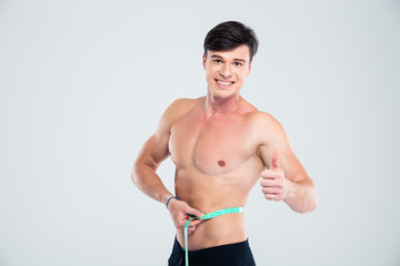 Fototapeta na wymiar Smiling fitness man measuring his body