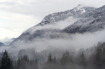 Obraz premium Mountain valley with snow and low clouds.